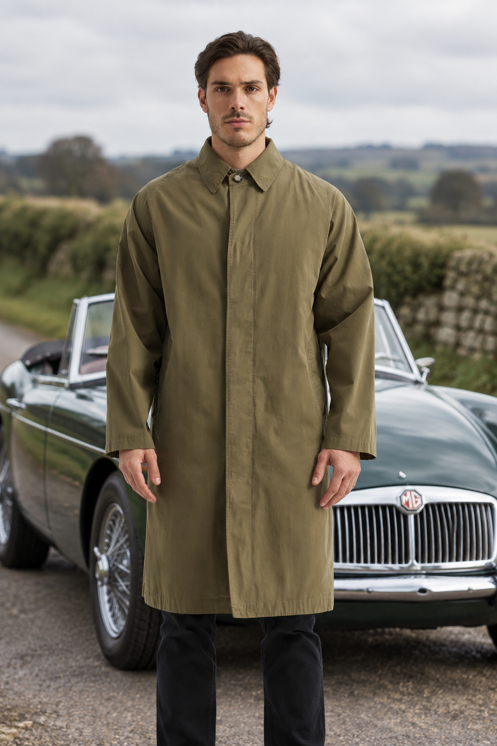 Man i khakifärgad car coat framför en klassisk MG-roadster